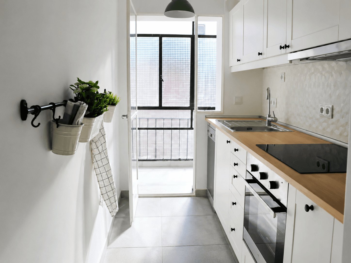 Cocina después de la reforma, con mobiliario blanco, encimera continua y salida al tendedero